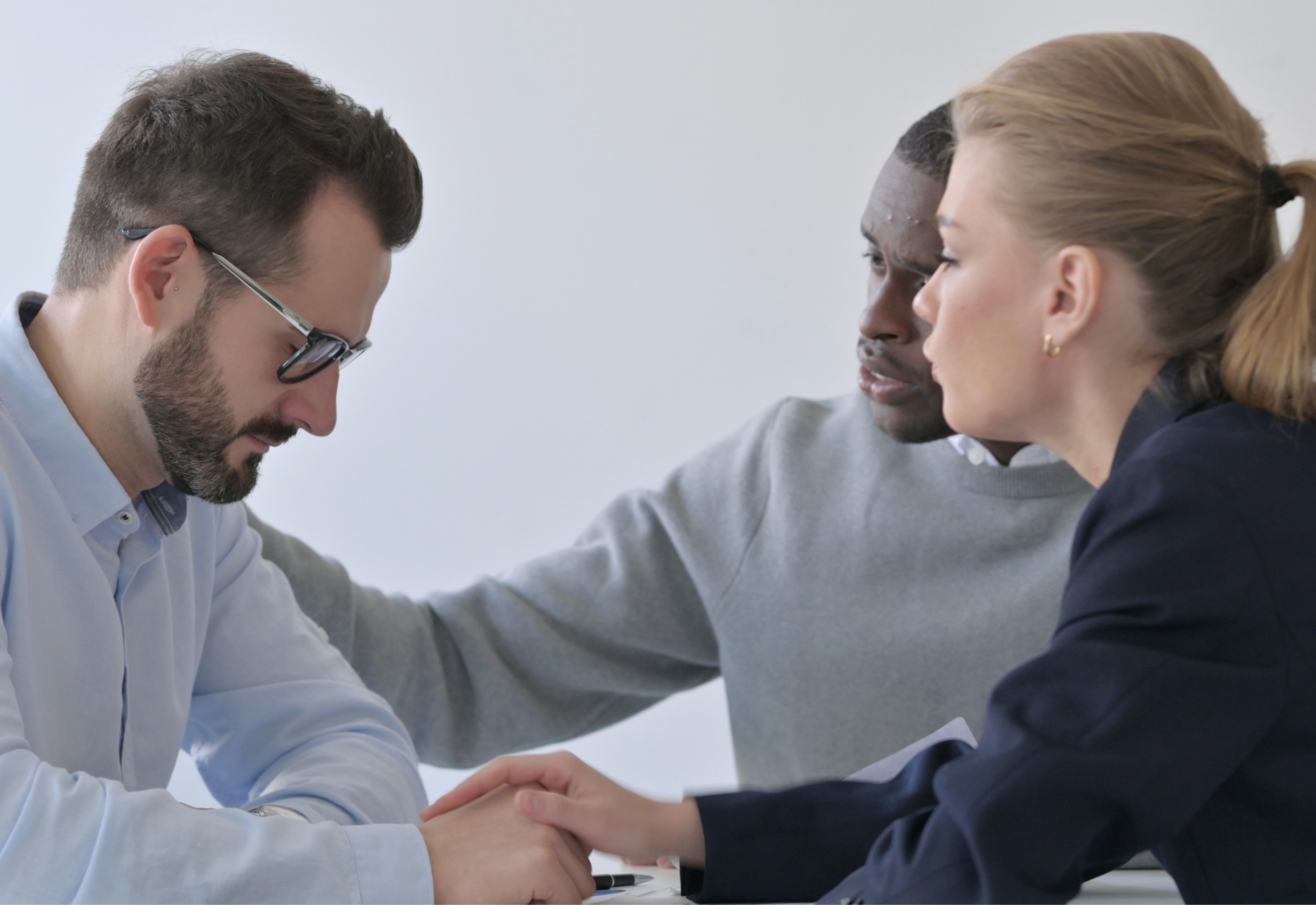 A man and woman comforting another man