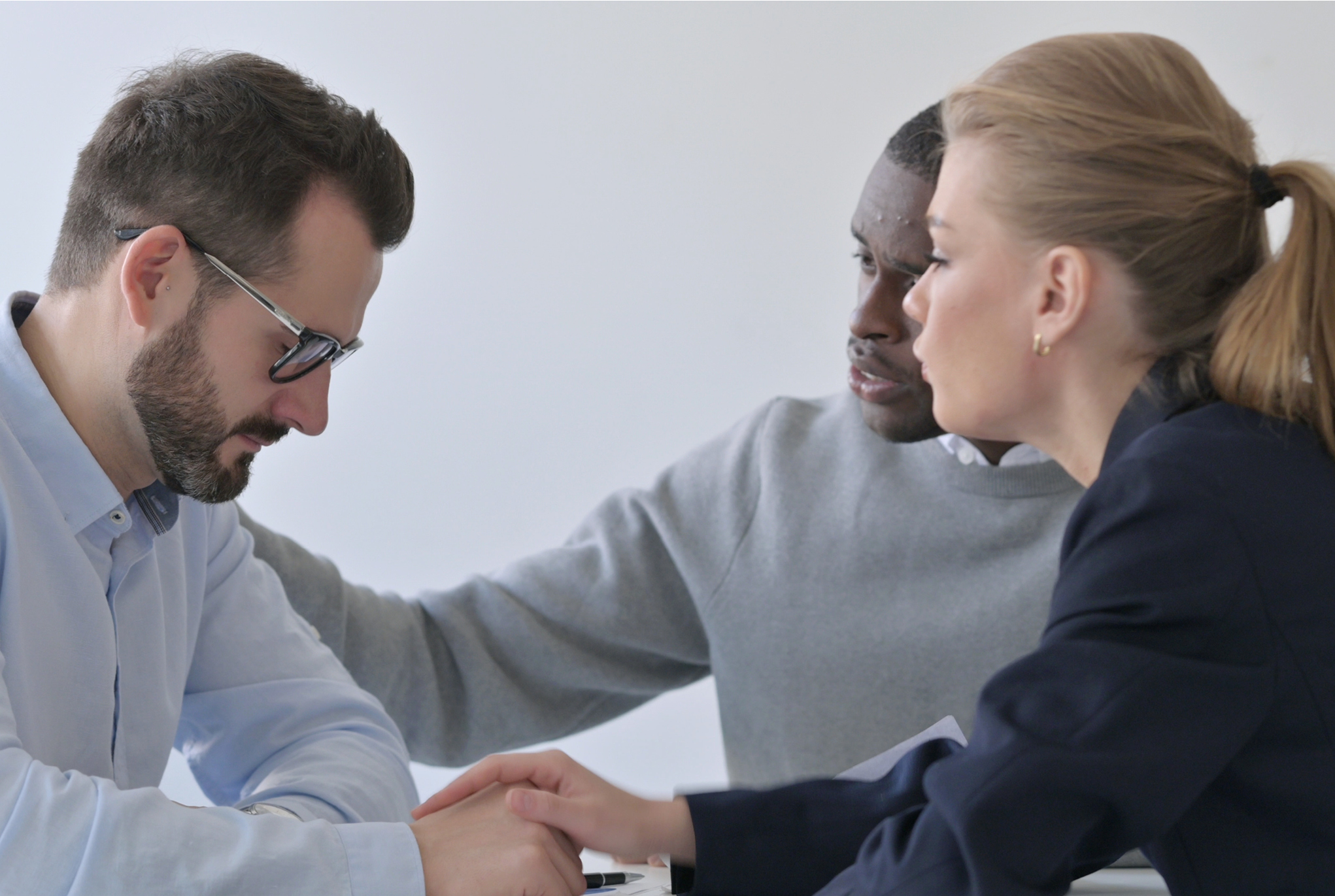 A man and woman comforting another man