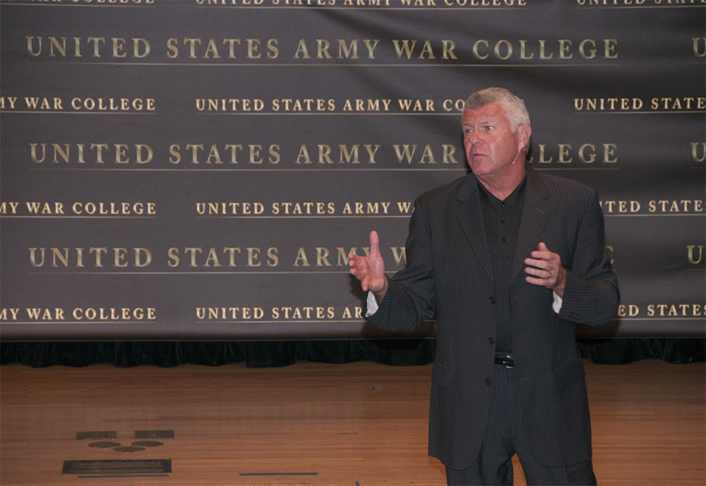 bob delany stands and speaks to a group on stage