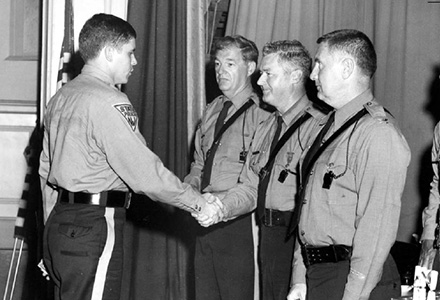 bob delany shakes hands while being sworn in to state police