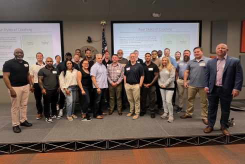 A group of training participants stand and pose for a picture