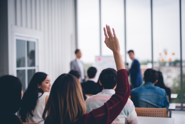 A woman raising her hand to ask a question during a presentation