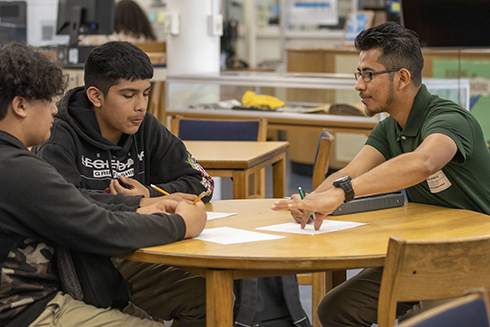 Mathematics Education student tutoring two students in the school library