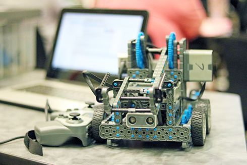 A VEX robot placed on a table next to a computer