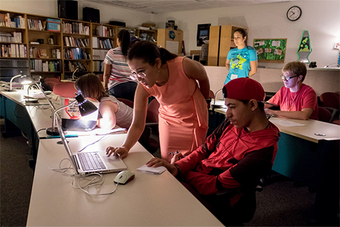 Animation camp instructor Dani Bowman working with a student on a laptop