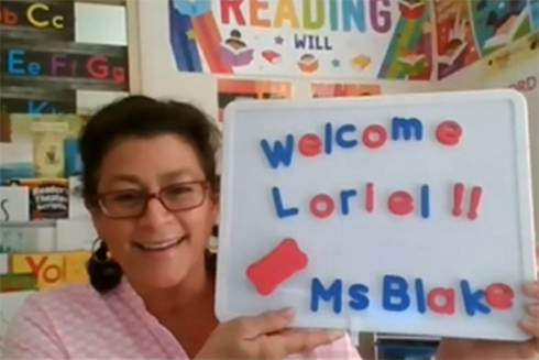 Consuelo Blake holding up a sign to welcome a student