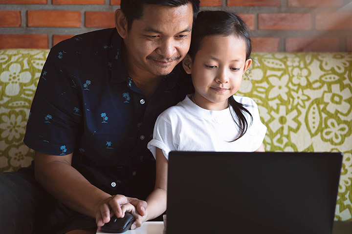 Father and daughter use laptop together