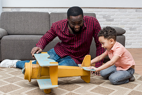 Father son playing with toy plane