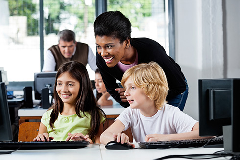 Teacher with students at computers in school