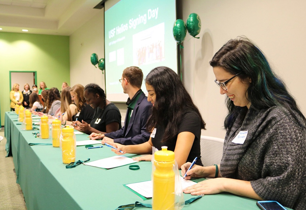 USF students sign pre-contract binders at a signing day event