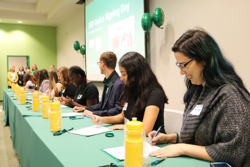 USF students sign pre-contract binders at a signing day event