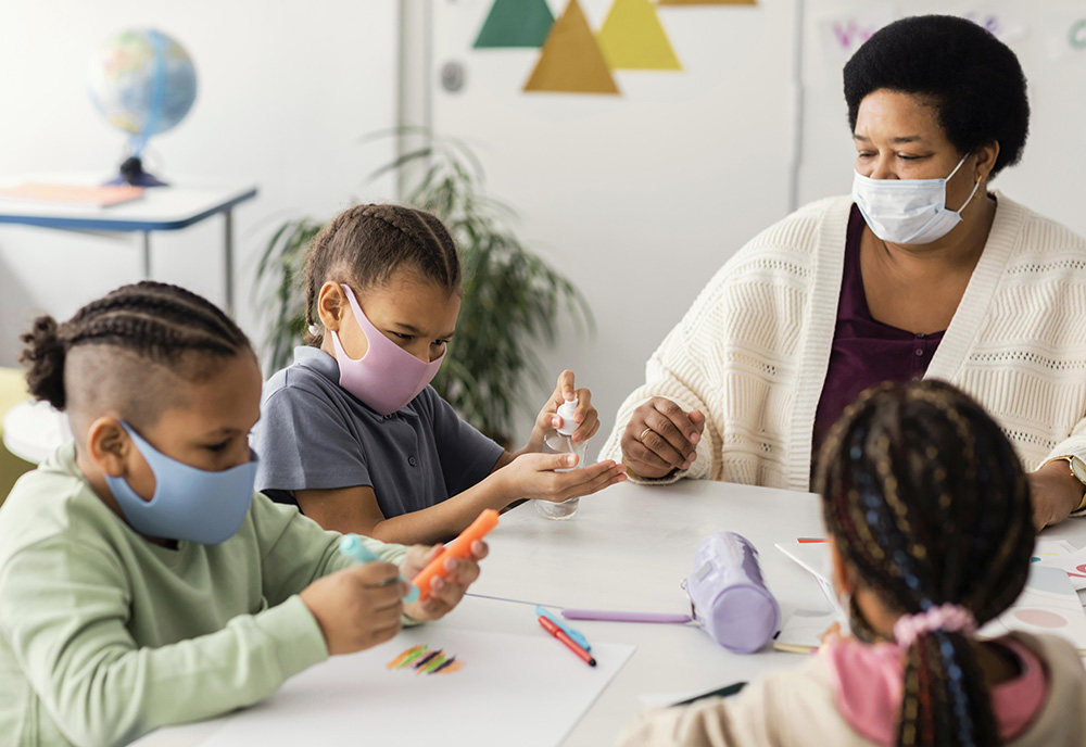 Kids with a teacher in a classroom disinfecting a table