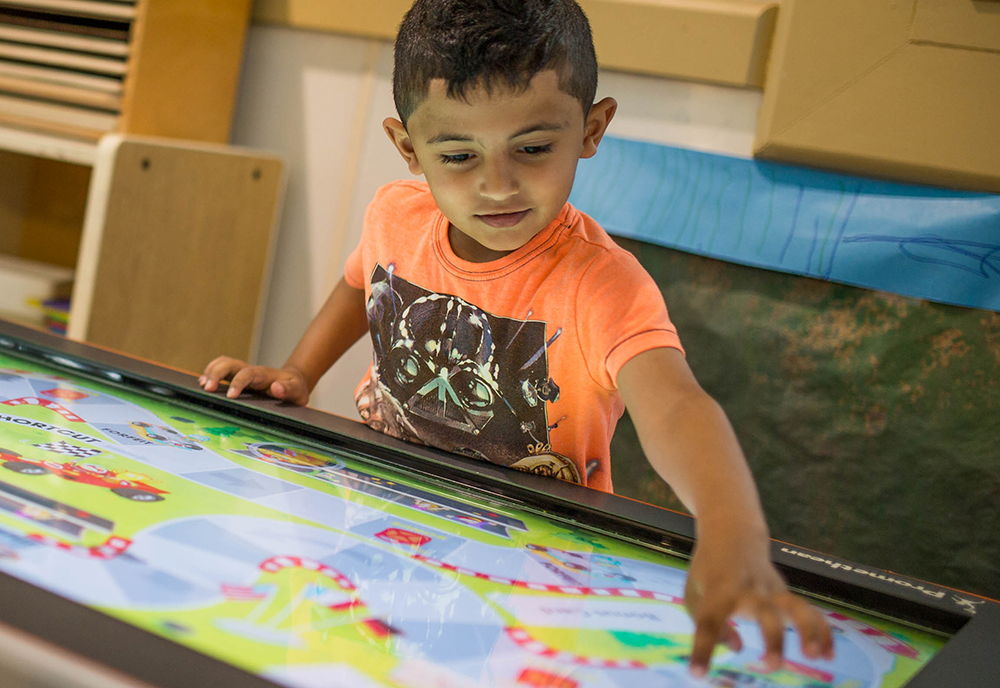 Preschool student uses tablet in classroom to play educational games 