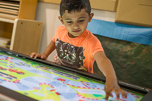 Preschool student uses tablet in classroom to play educational games 