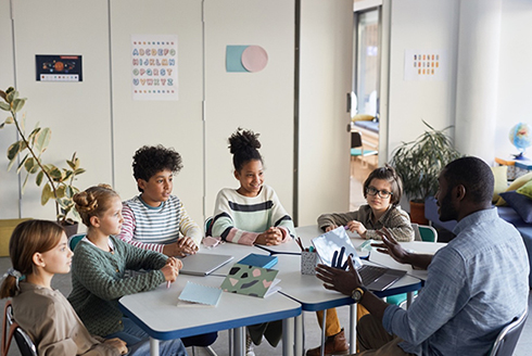 Students with teacher in a classroom small group discussion