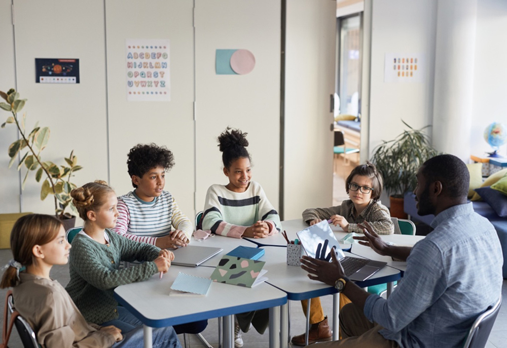 Students with teacher in a classroom small group discussion