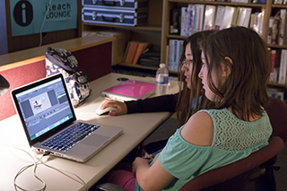 teacher working with student on a laptop