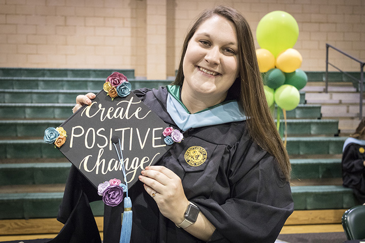 Student with decorated graduation cap that says create positive change