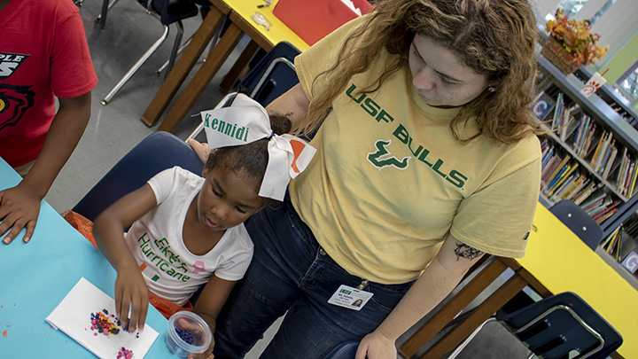 USF student with elementary student working on an art project