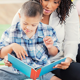 Teacher reading a book with student