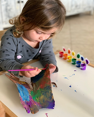 a child painting a stick from outside