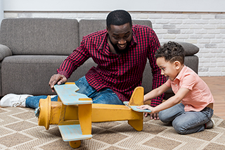 Father and son playing with a toy airplane at home