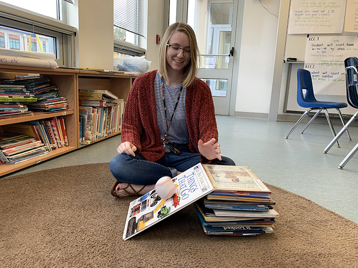 Malina Pakulak teaches a lesson with books and a baseball