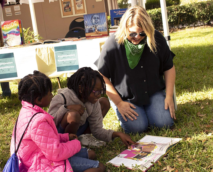 Assistant professor reads with girls in the grass