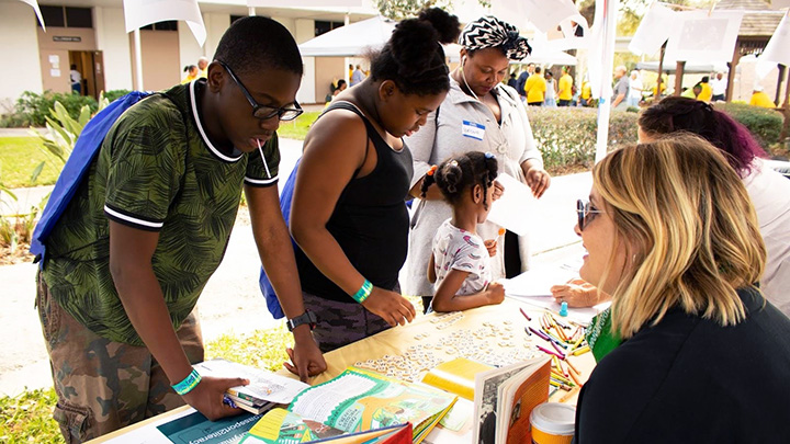 USF professor and graduate student instruct students in a literacy activity at a local community event