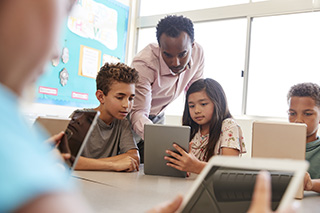 teacher working with students on tablets