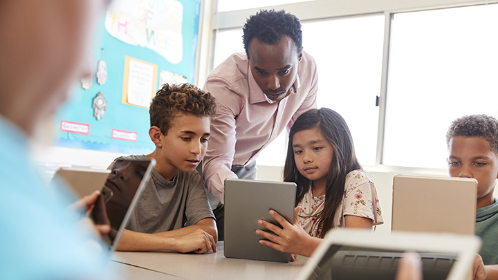 Teacher with students in a classroom on laptops