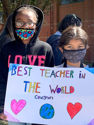 Maude Graham with students holding up a sign