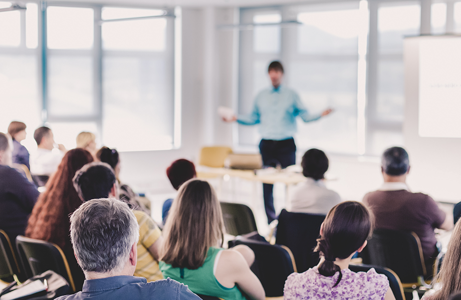 man standing in front of an auditorium of people presenting