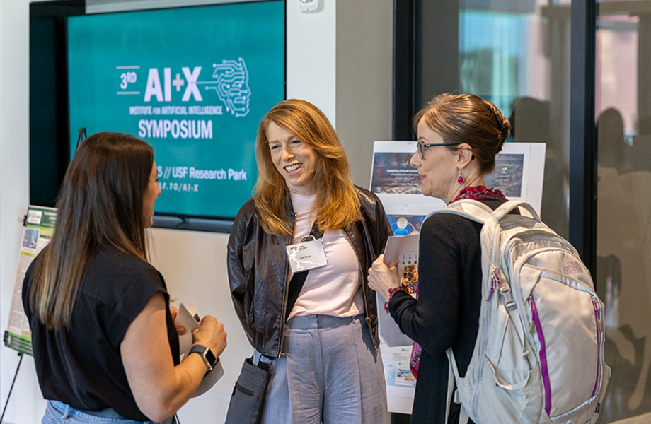 three people talk at a symposium