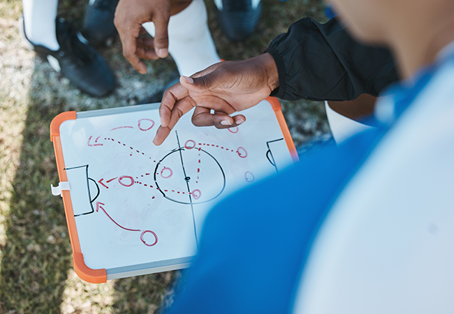 a close up of hands holding a clipboard with a soccer diagram play 