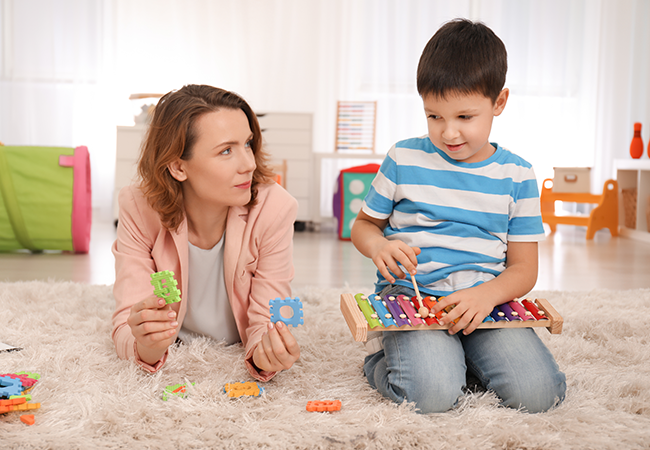 a woman and child sit on a floor playing with blocks and letters