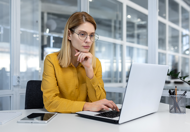 a woman sits on a laptop in office