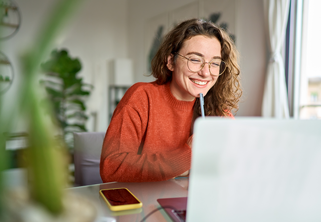 a woman sits at a laptop smiling