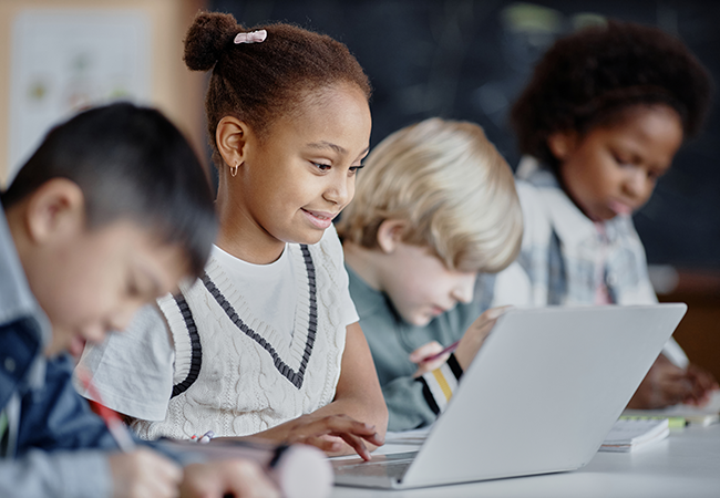 students seated in front of laptops and taking notes