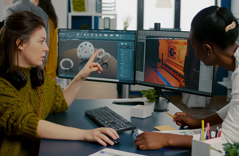 2 women sit at a computer building a game on the computer