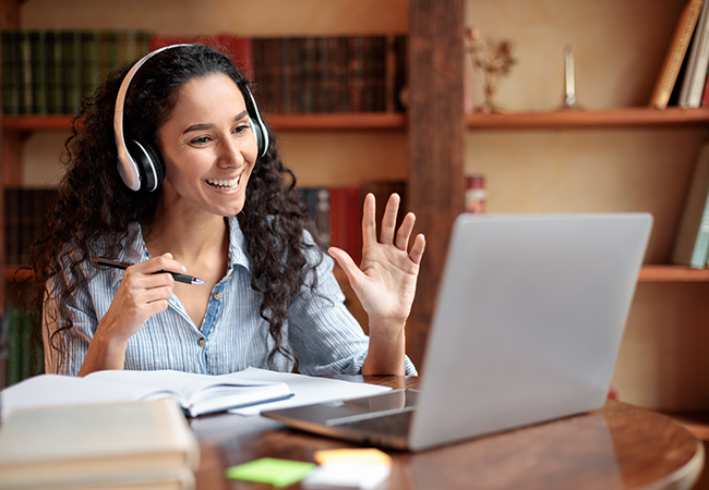 smiling woman wearing headphones in front of laptop