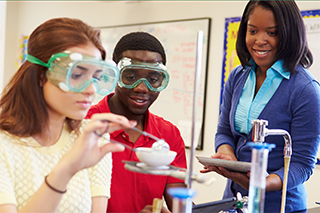 teacher with students conducting a chemistry lab experiment