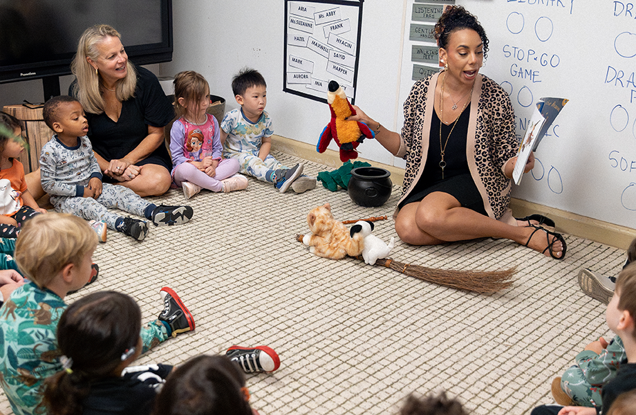 teacher seated and reading to a circle of children