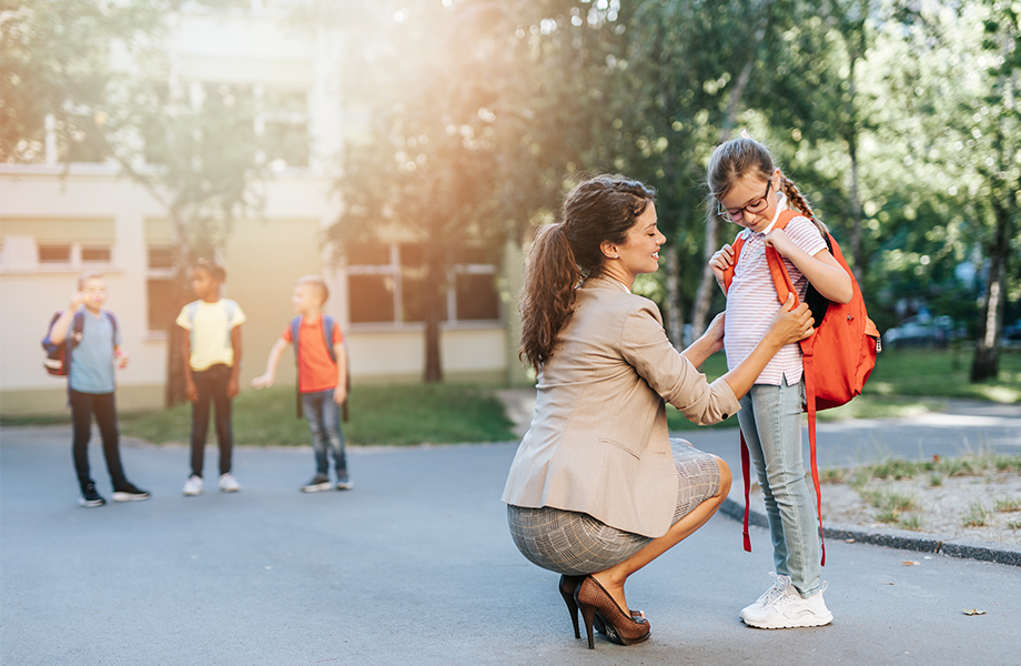 guardian helping young student with backpack