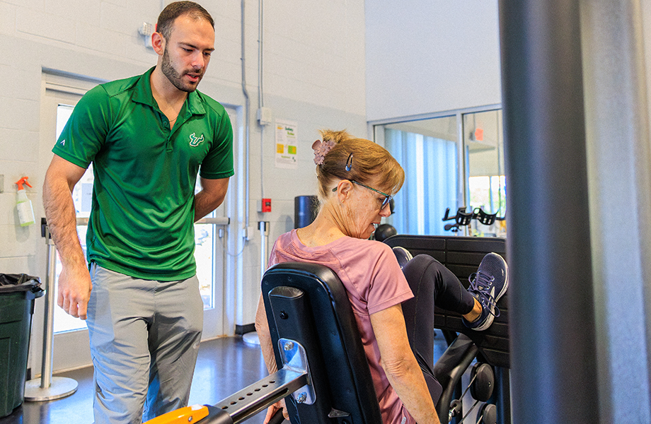 Exercise science student working with a client on gym equipment