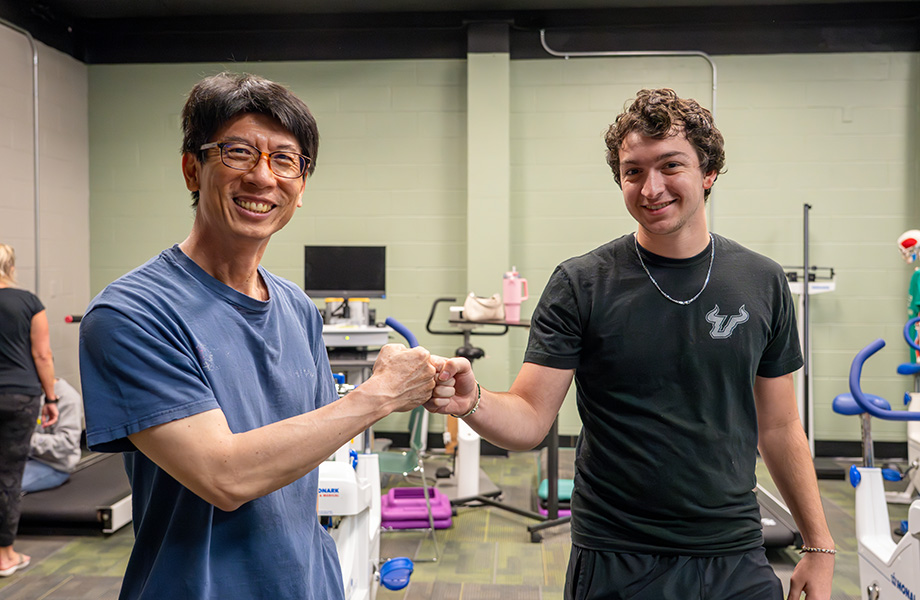 two men smiling at camera in gym fist bumping each other