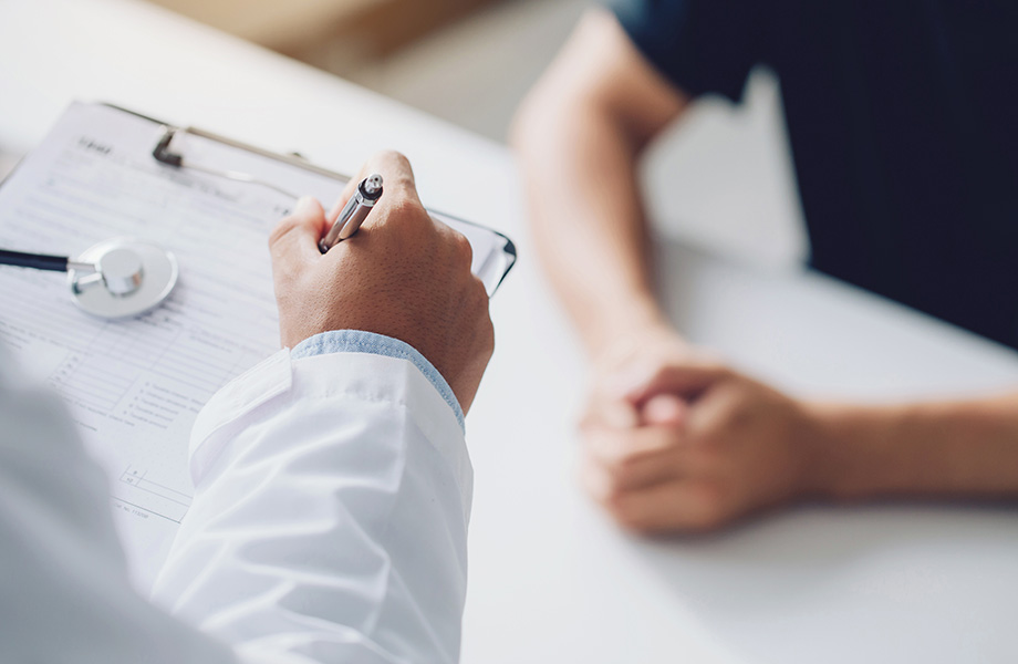 a close up of 2 health professional's hands one holding a pen with a clipboard and a stethascope