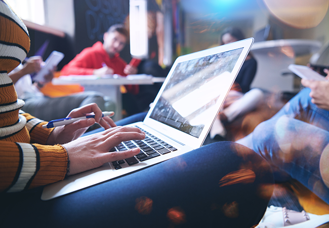 person on laptop with others also using computers in the background