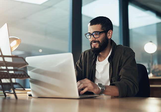 man sits at computer smiling