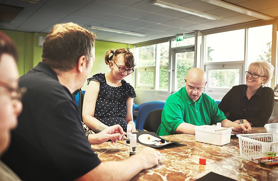 a group of special needs person sit around a table with two instructors